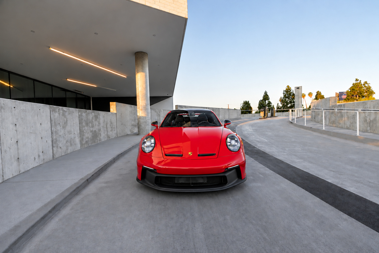 Guards Red Porsche 911 GT3 head on with the low front splitter and the wing visible over the roof