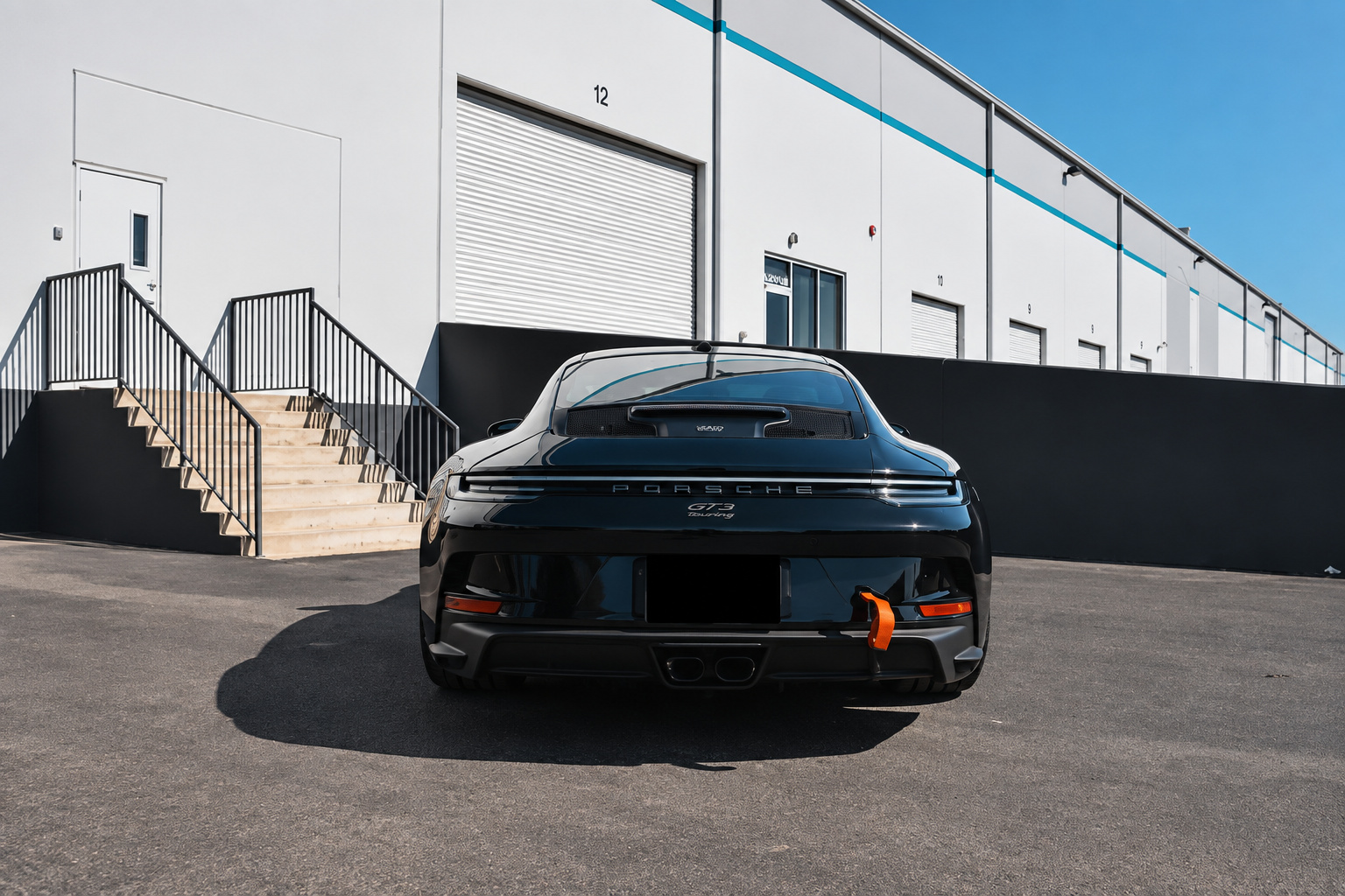 Rear view of the black Porsche 911 GT3 Touring with no wing and the GT3 touring script on the deck
