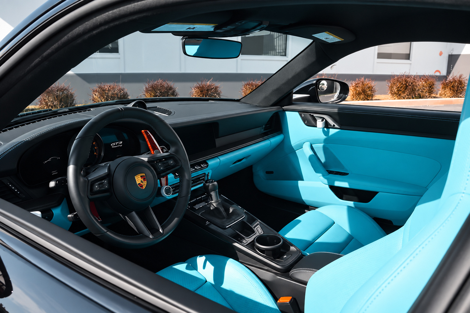 Driver side of the Porsche 911 GT3 Touring cabin with blue dash, blue door panels and black steering wheel