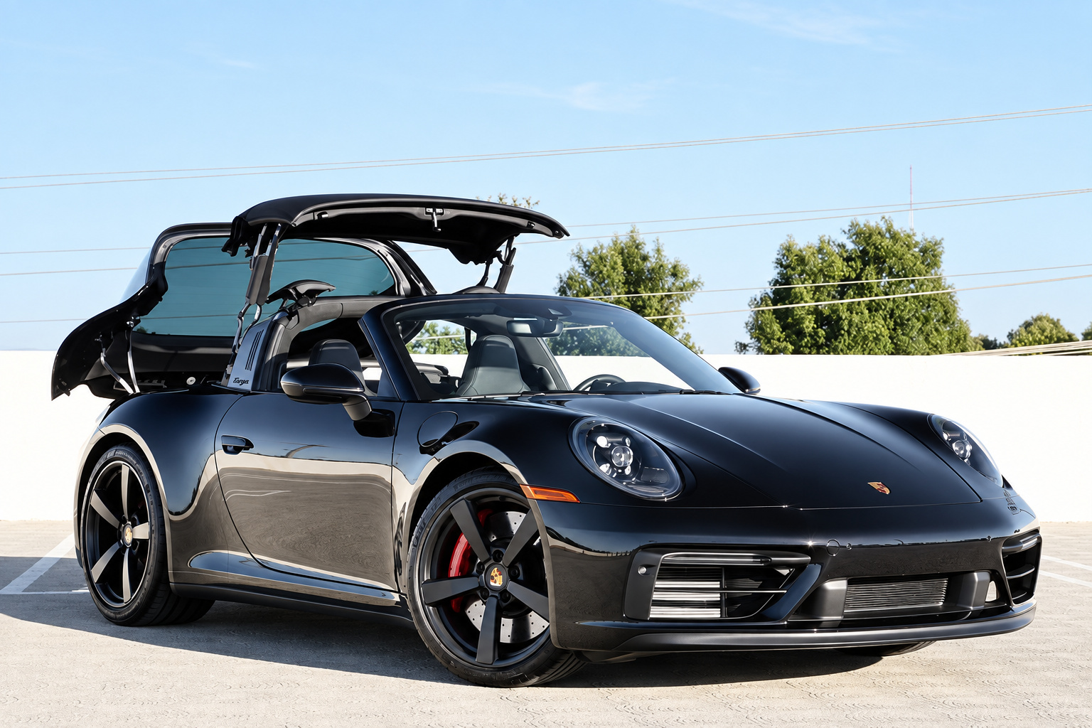 Black Porsche 911 Targa 4 GTS with the roof mid-fold, glass window lifted, on a parking roof
