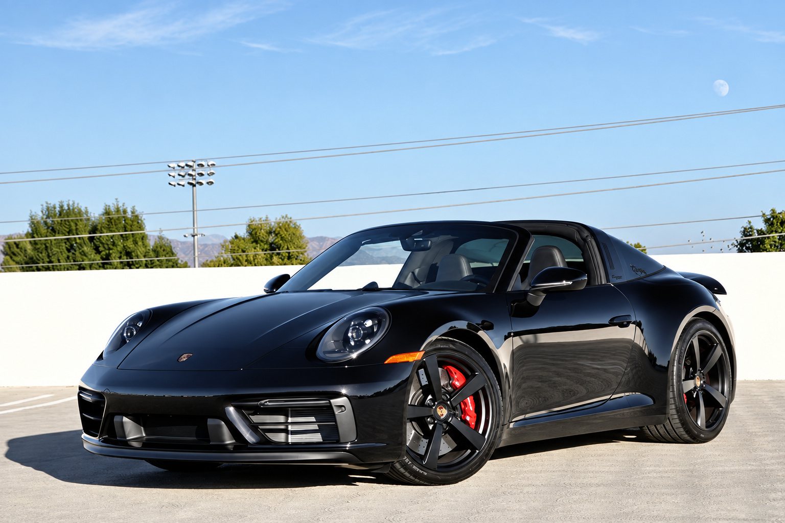 Front three-quarter of the black Porsche 911 Targa 4 GTS, roof closed, red calipers behind black wheels