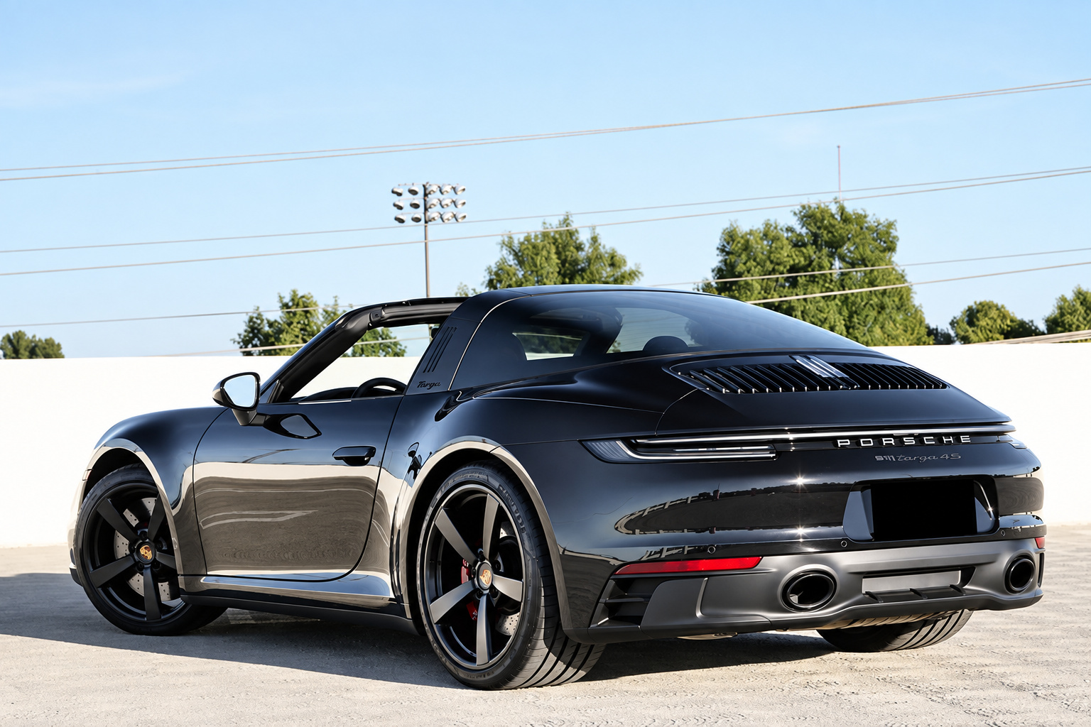 Black Porsche 911 Targa 4 GTS from the rear corner showing the black Targa bar and glass canopy