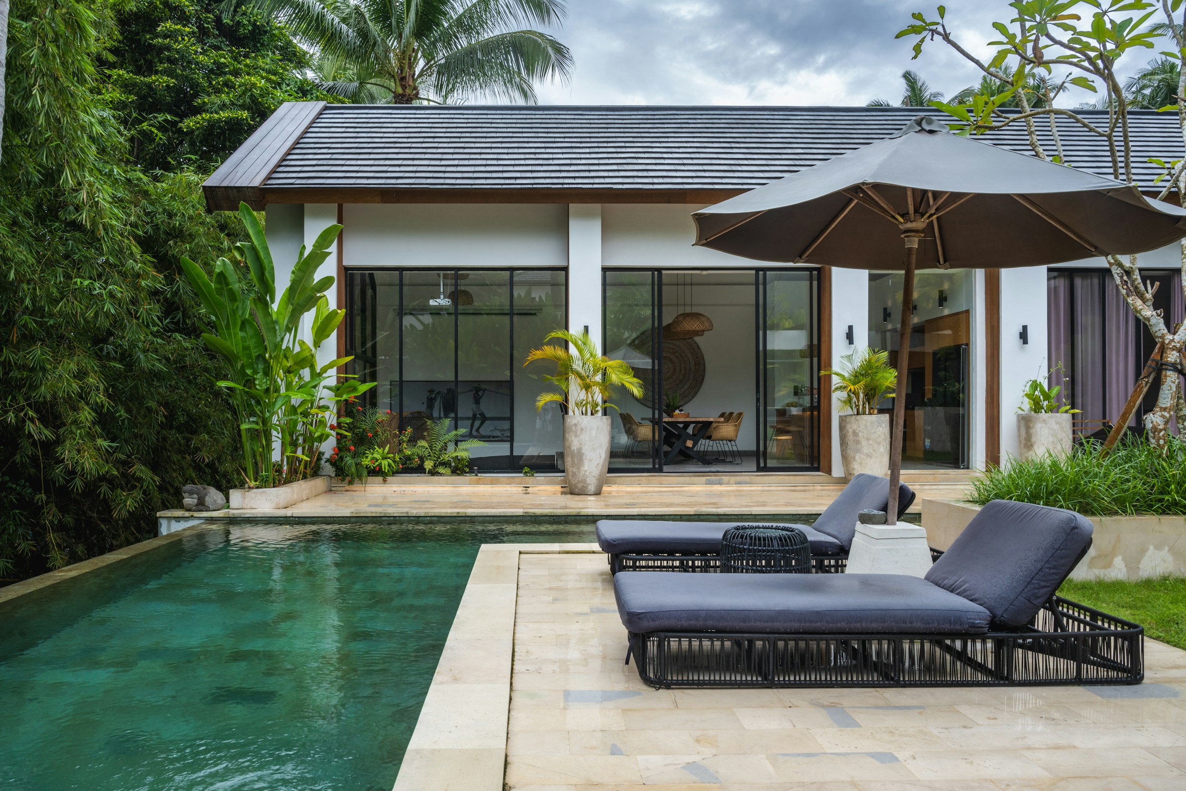 Luxury villa rental with a private pool, sun loungers and an umbrella in a tropical garden