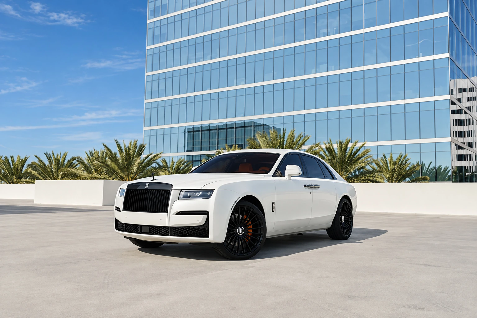 White Rolls Royce Ghost with a black grille and black wheels, front three-quarter on a rooftop below glass office towers