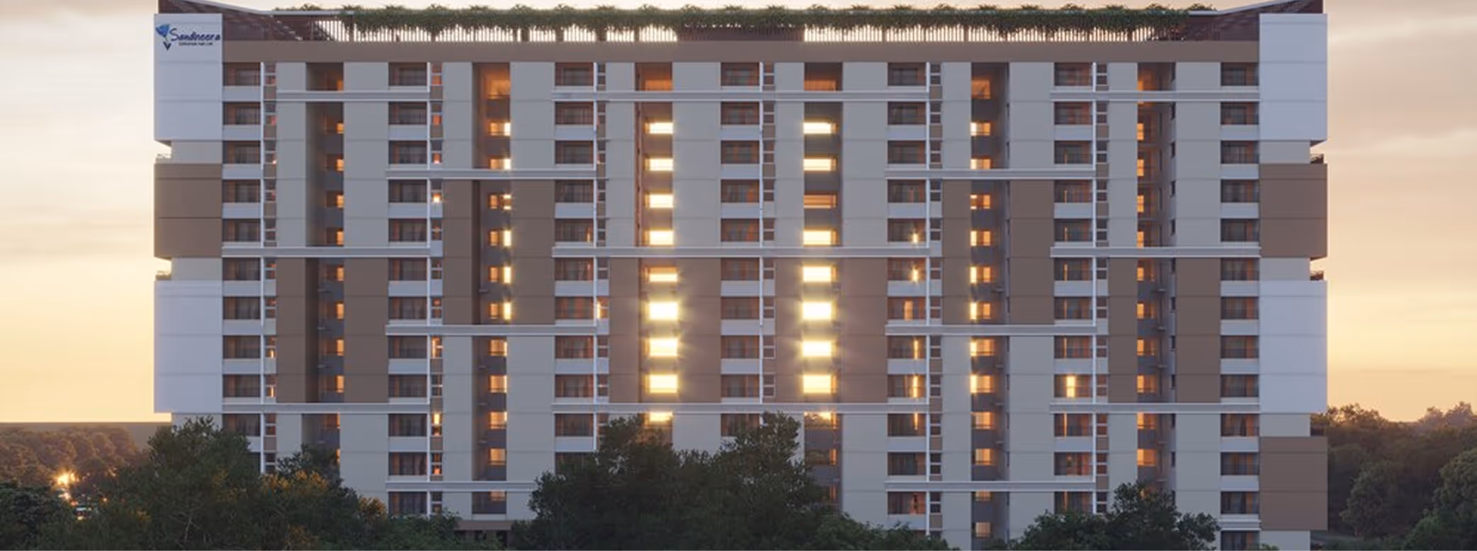 Modern multi-story residential building with illuminated windows at sunset, surrounded by trees.