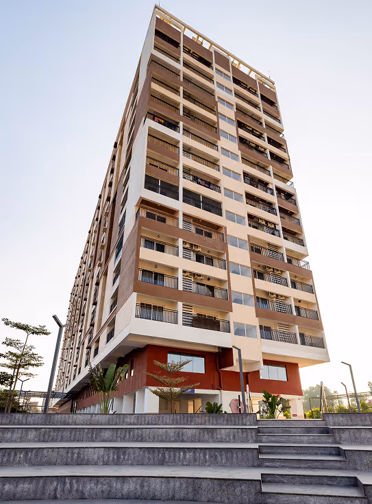 Modern multi-story apartment building with balconies viewed from low steps against clear sky.
