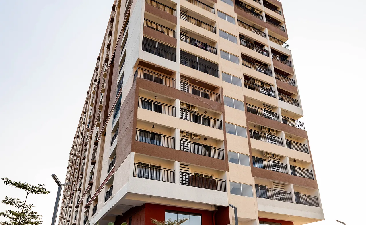 Low angle view of a modern multi-story apartment building with balconies and beige and brown exterior.