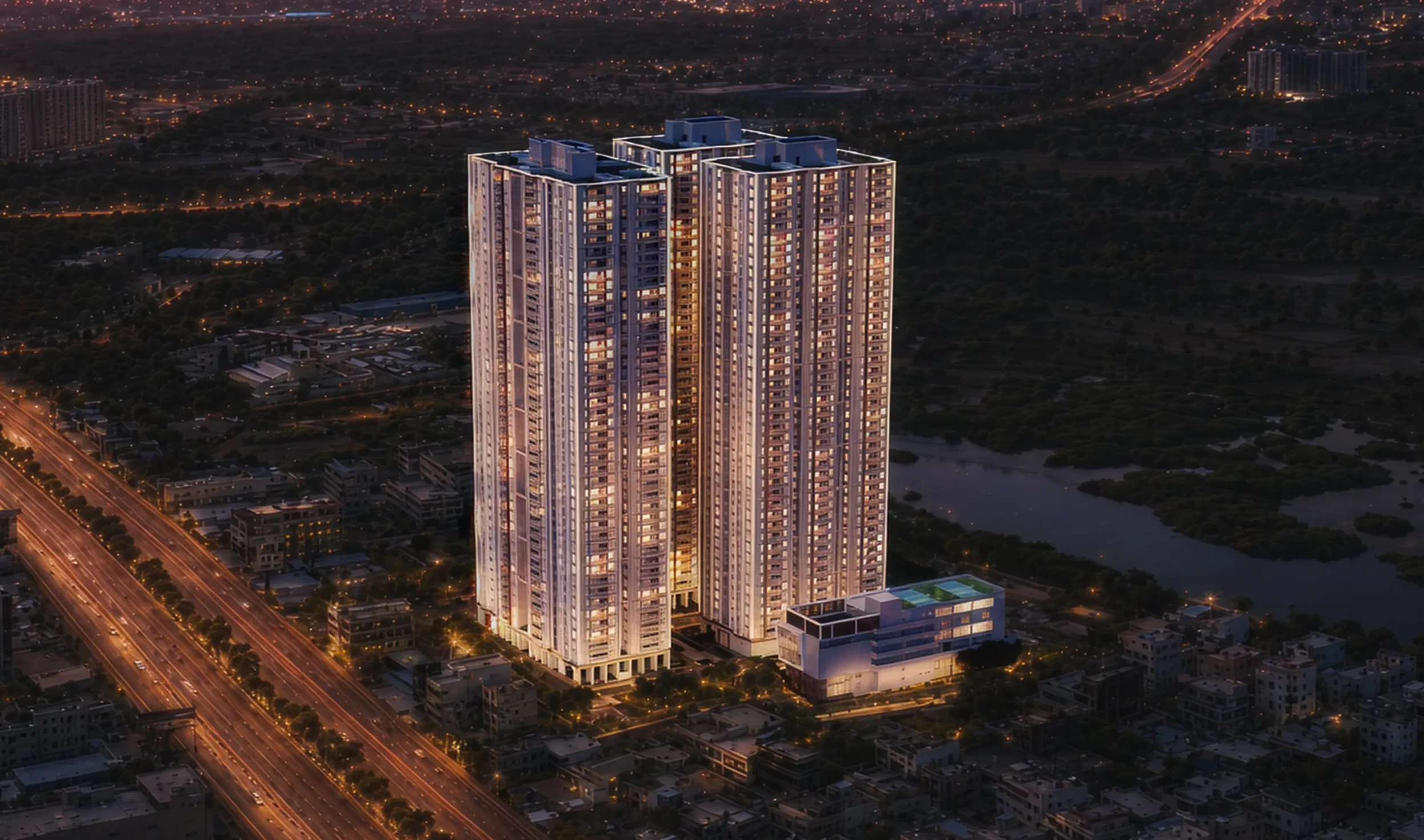 Illuminated twin high-rise buildings with surrounding city and roads at dusk.