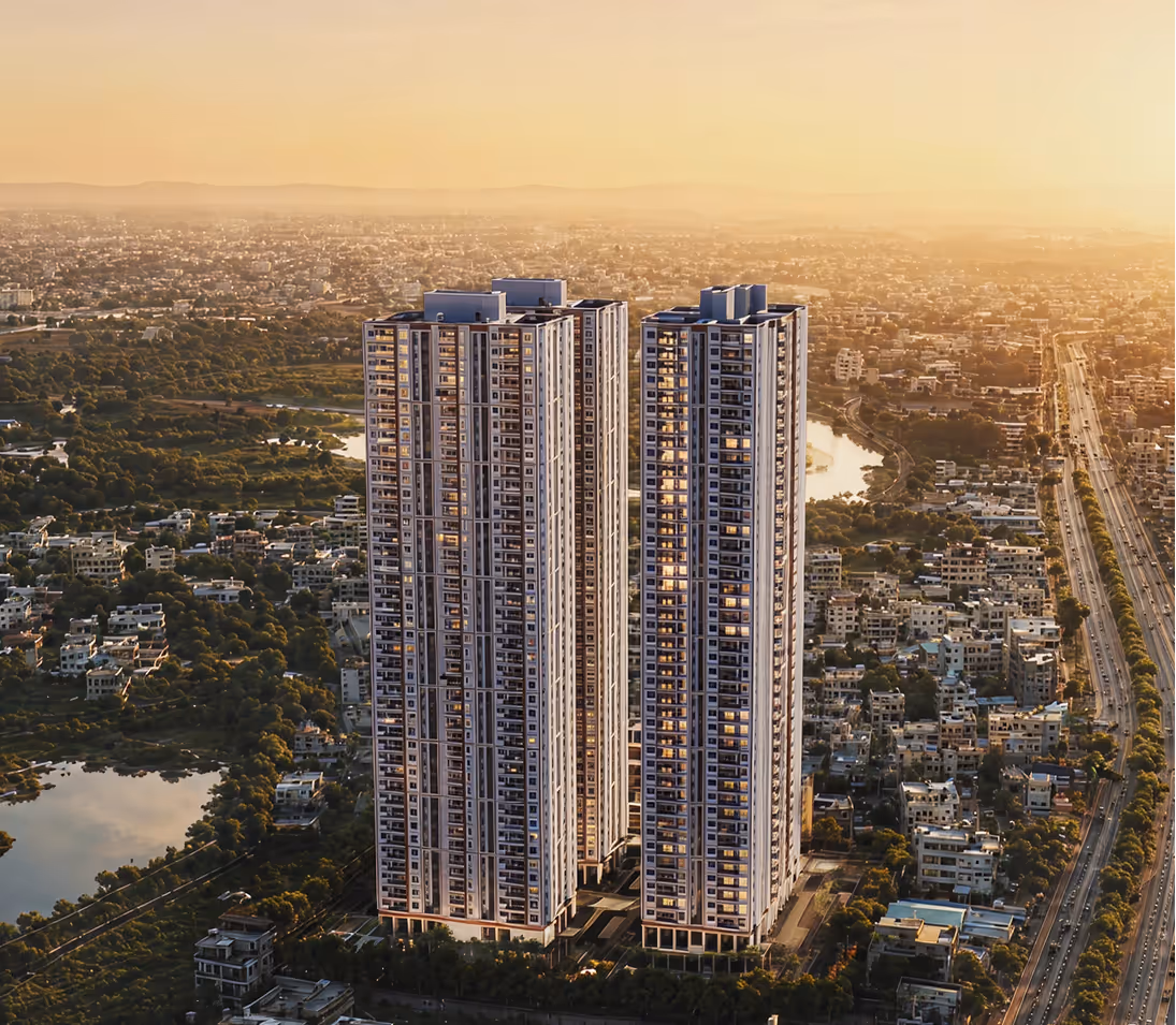 Two modern residential skyscrapers at sunset surrounded by city buildings and roads.