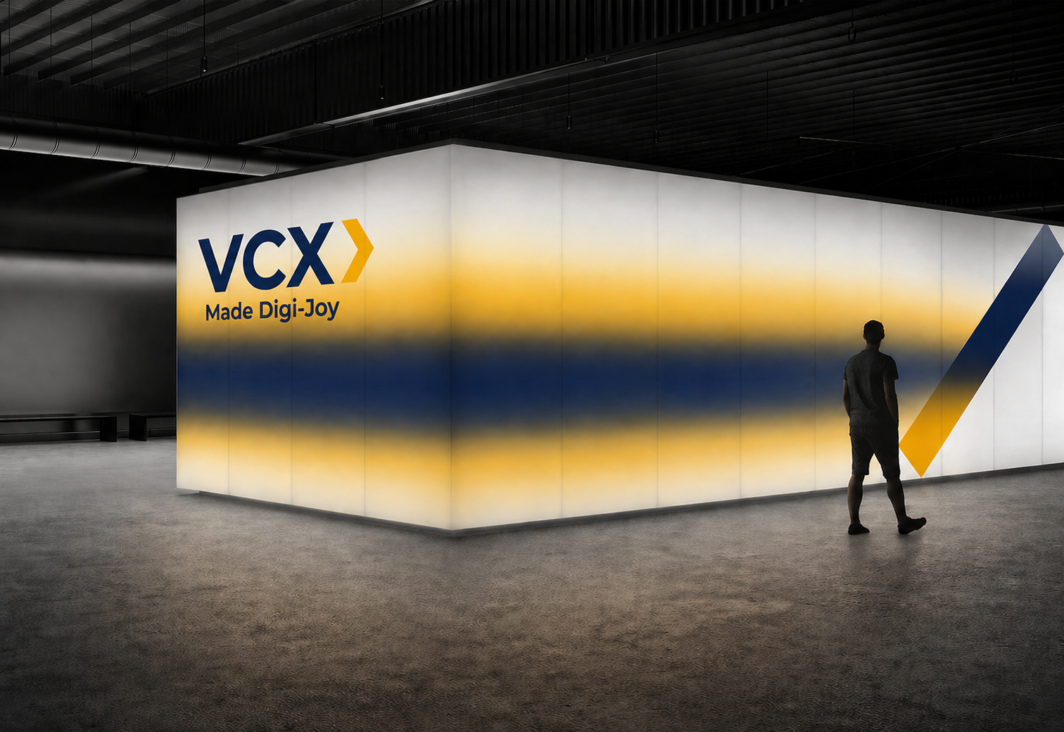 Person standing in front of a large illuminated wall with blue and yellow stripes and VCX logo.