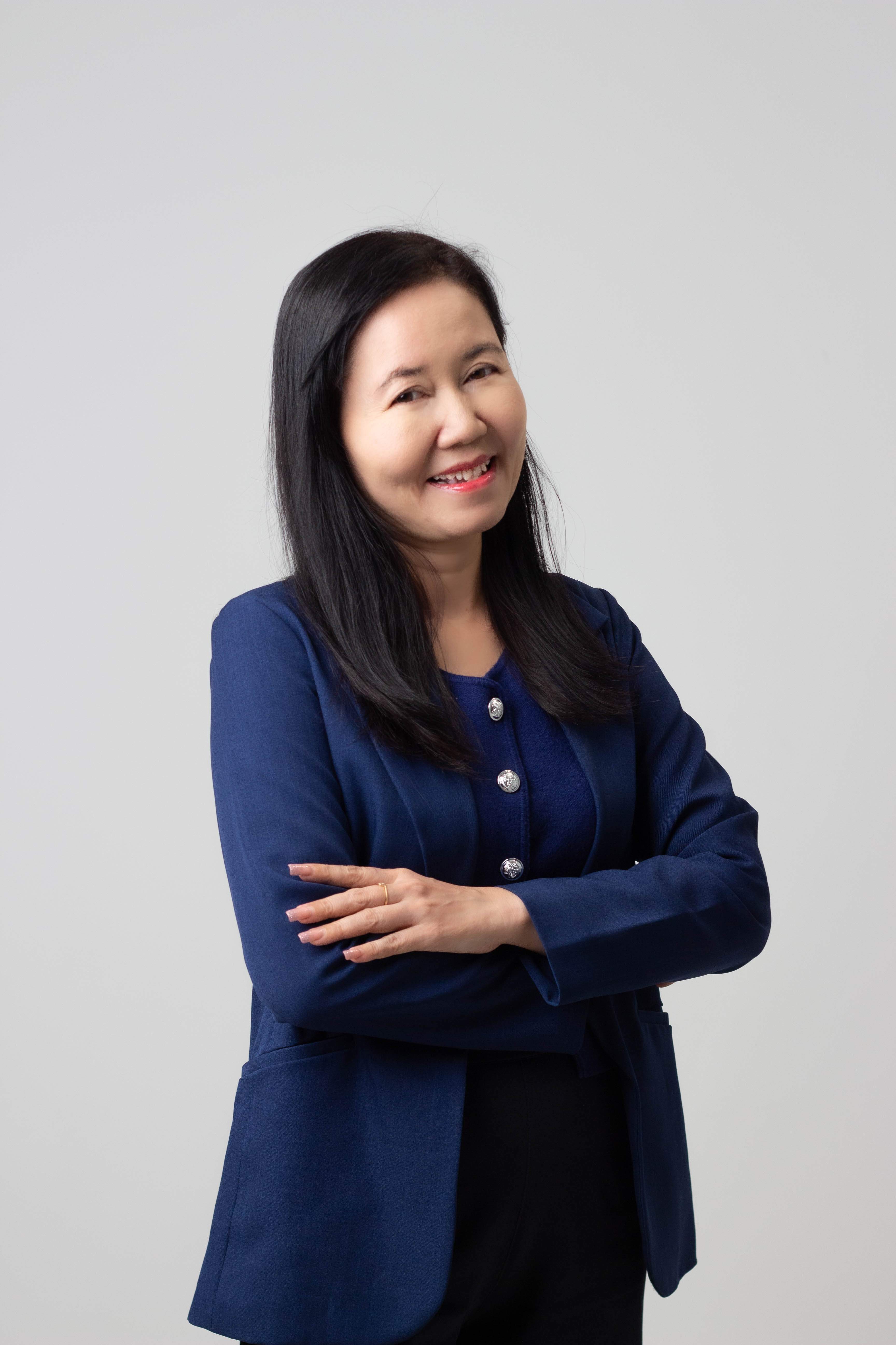 Smiling woman with long black hair wearing a blue blazer and crossing her arms.