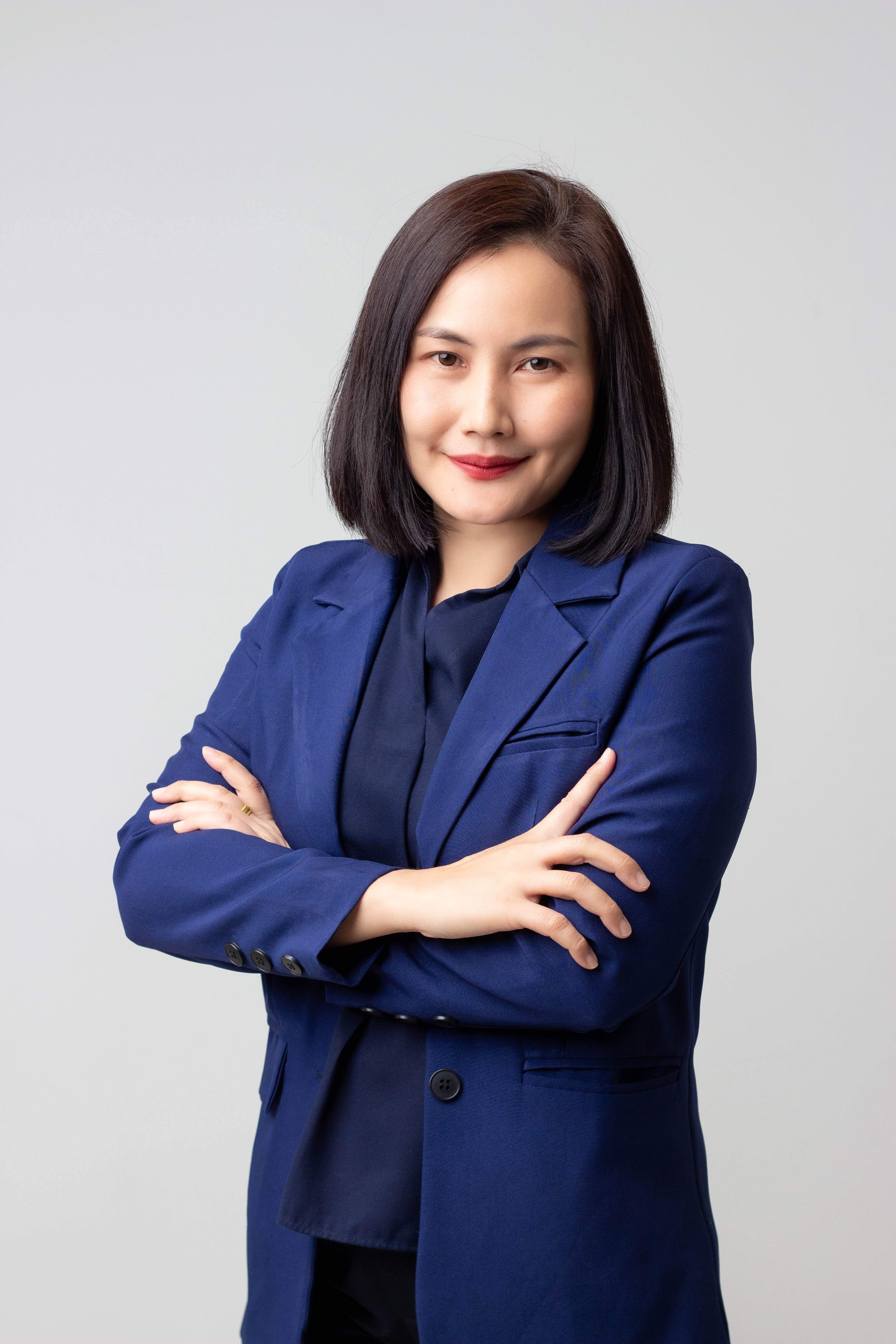 Confident woman with dark hair wearing a blue blazer, arms crossed, smiling at the camera.