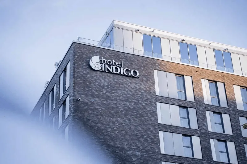 Außenansicht des Hotel Indigo mit moderner Backsteinfassade und großen Fenstern unter klarem Himmel.