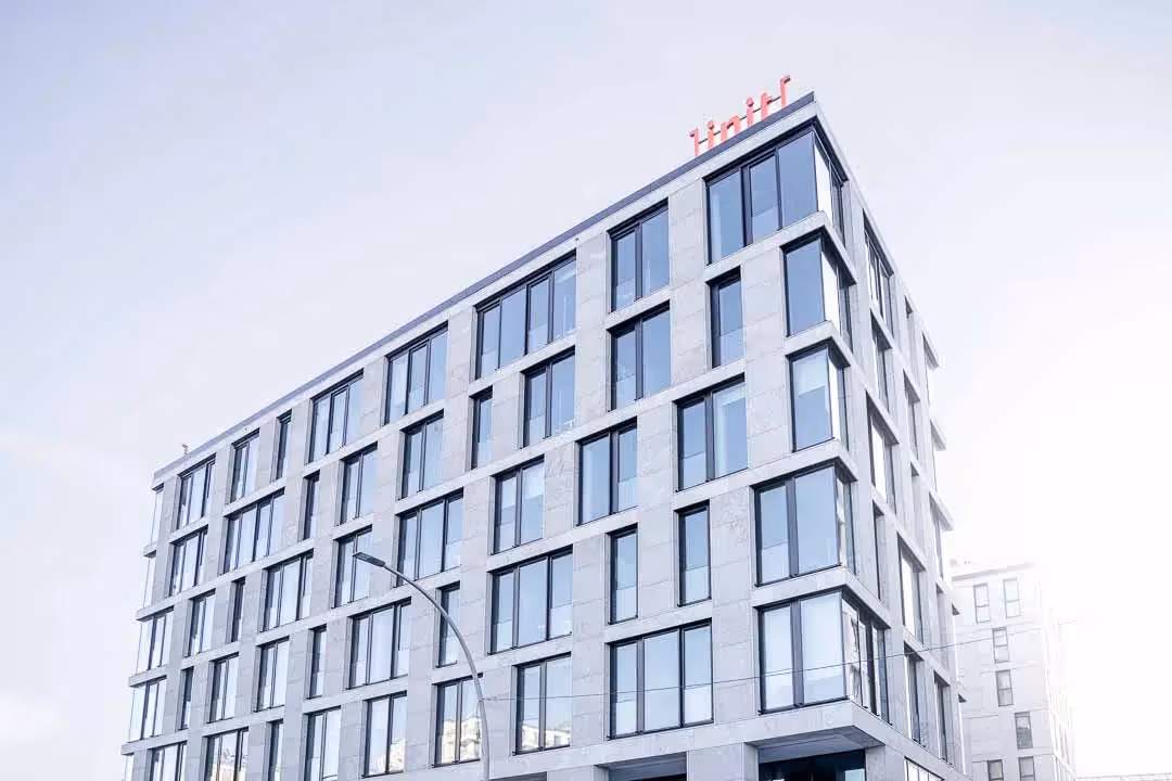 Moderne Gebäudefassade vom Eastside Office init AG mit großen Fenstern und dem Schriftzug 'init' oben auf dem Dach.