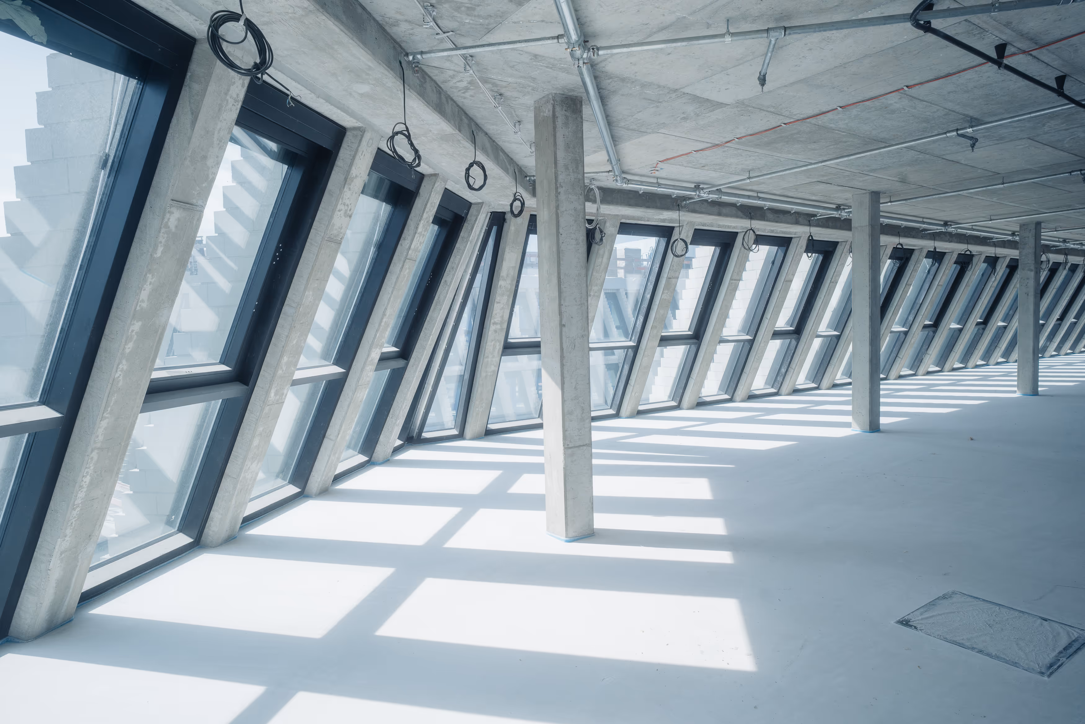 Großer, heller Raum im Tacheles Berlin mit geneigten Fenstern und sichtbaren Betonsäulen in moderner Architektur.