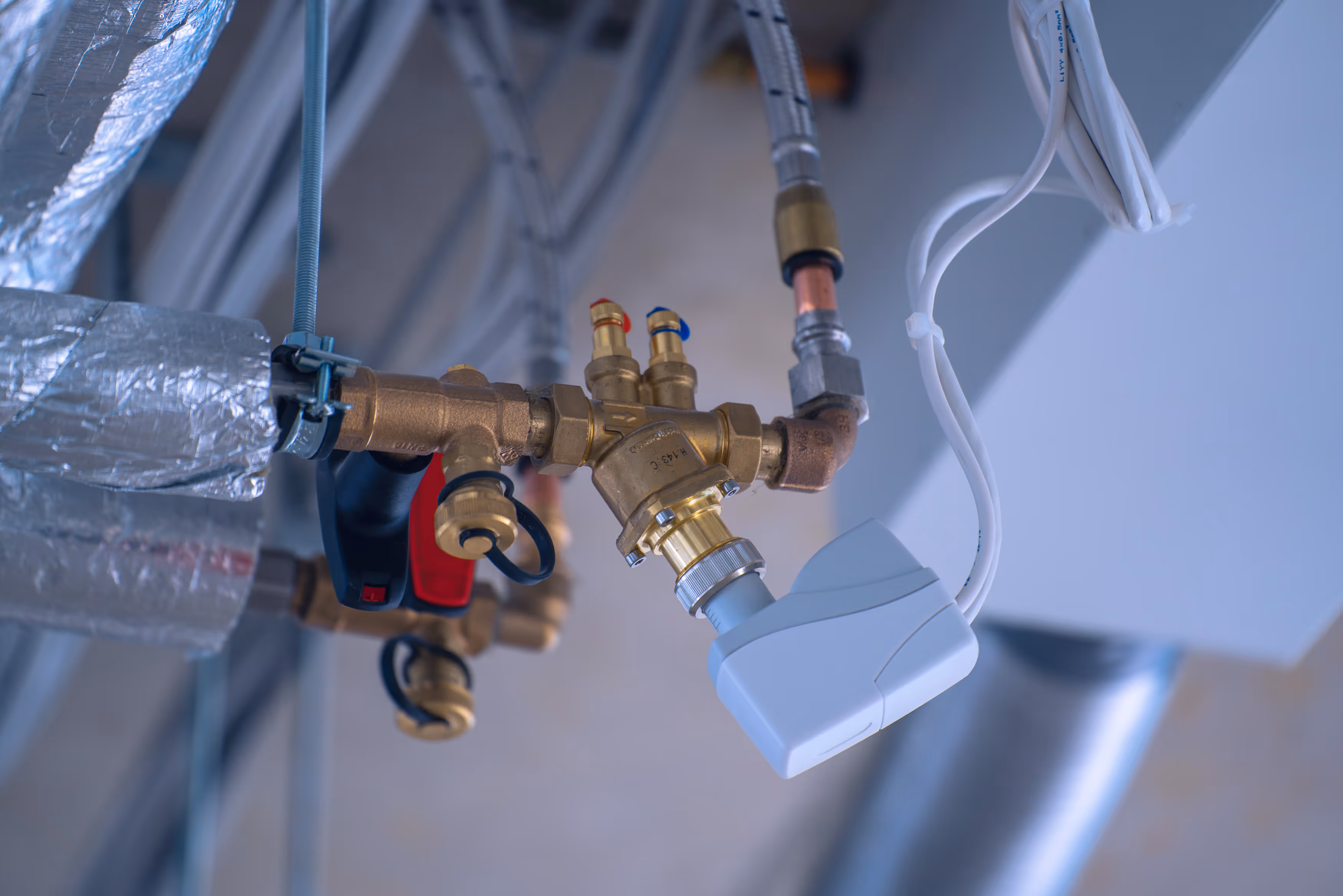 Nahaufnahme eines Heizungsventils mit Temperaturregler und isolierten Leitungen.