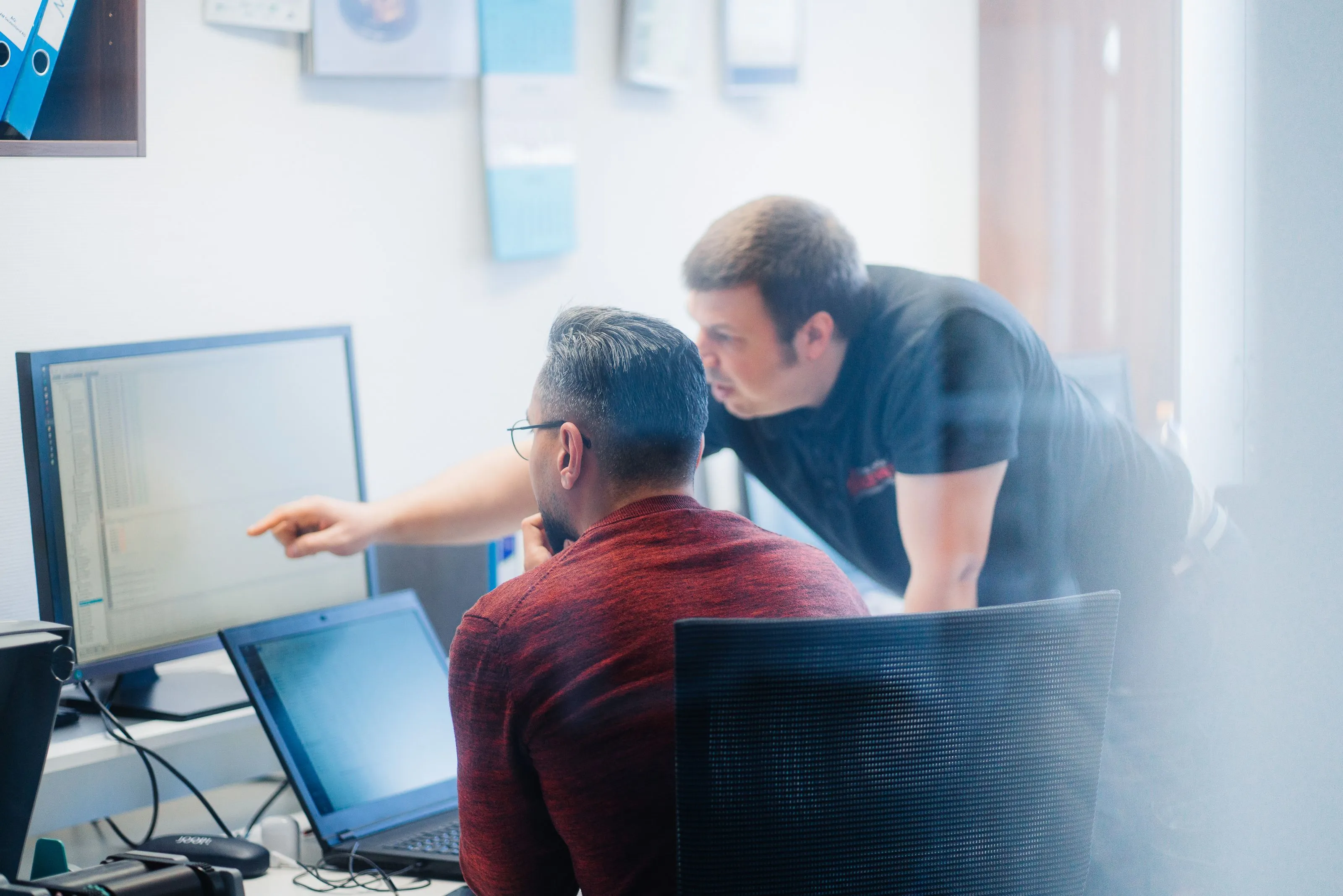 Zwei Mitarbeiter von IB Walther diskutieren und blicken auf einen Computerbildschirm in einem Büro.