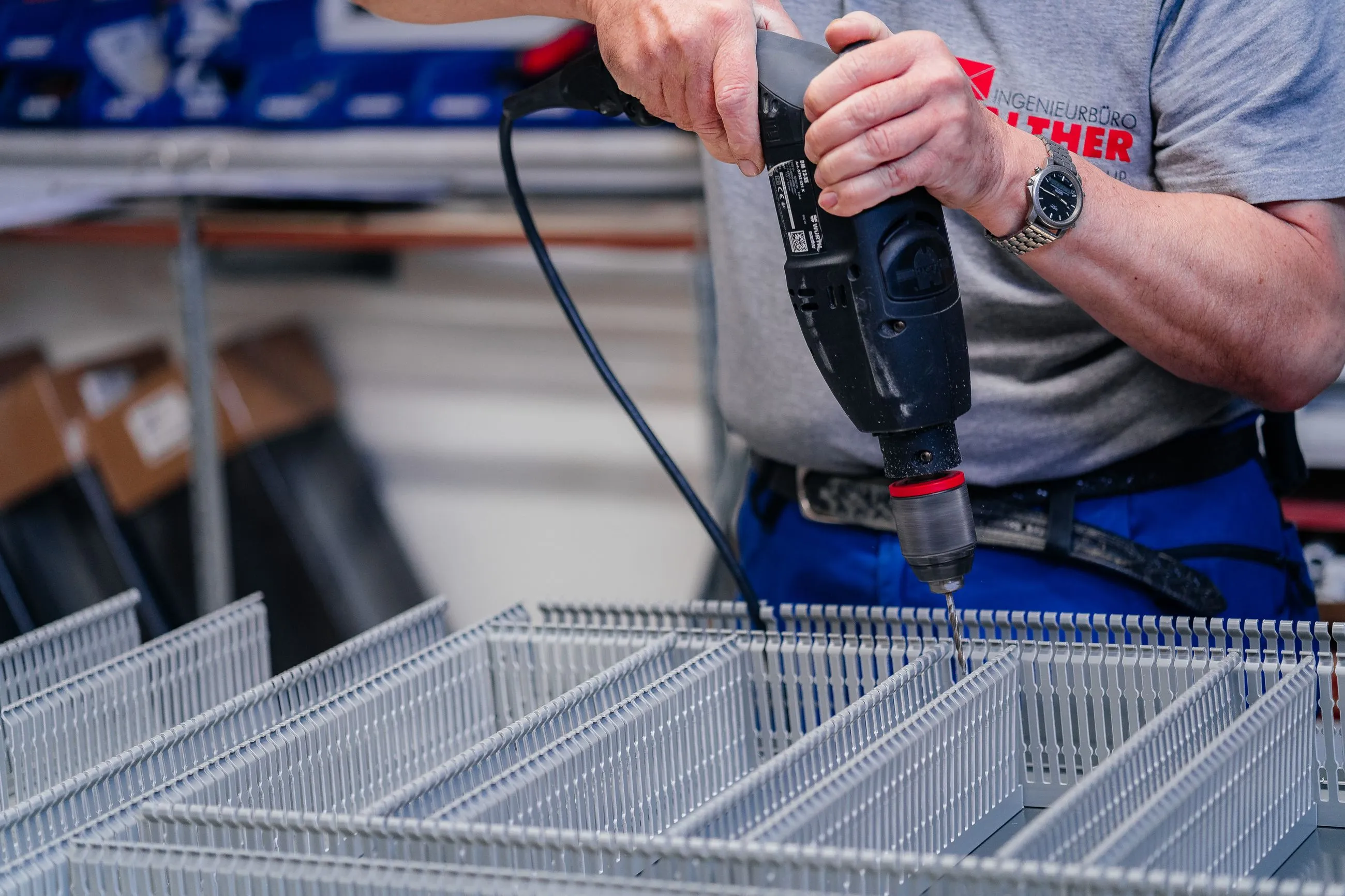 Nahaufnahme eines Mannes, der mit einem Akkuschrauber Löcher in ein weißes Kunststoffgehäuse bohrt.