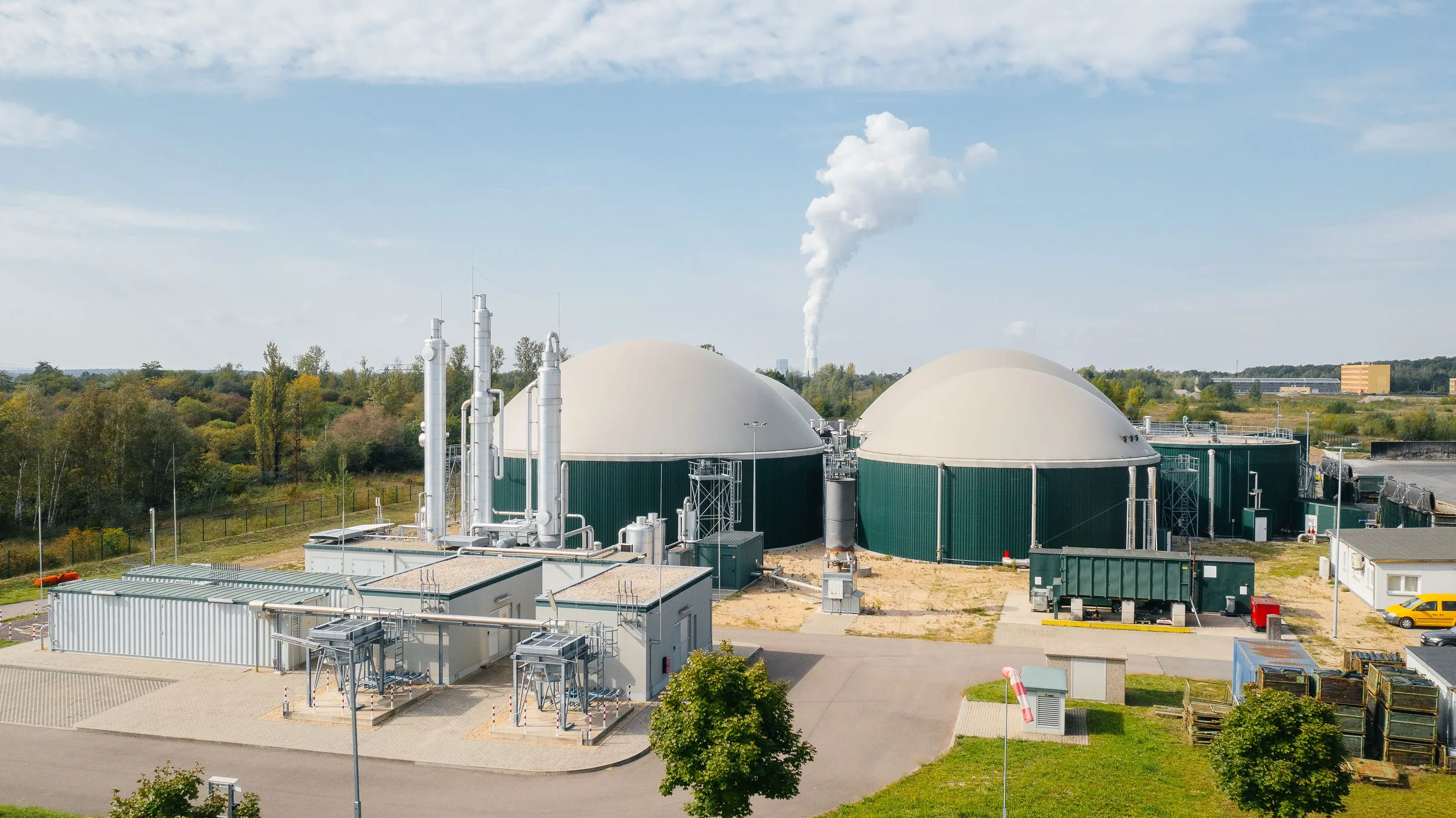 Biogasanlage mit zwei großen, kuppelförmigen Lagertanks und technischer Infrastruktur unter einem bewölkten Himmel.