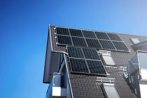 Dach eines Hauses mit mehreren Solarzellen unter klarem blauem Himmel.