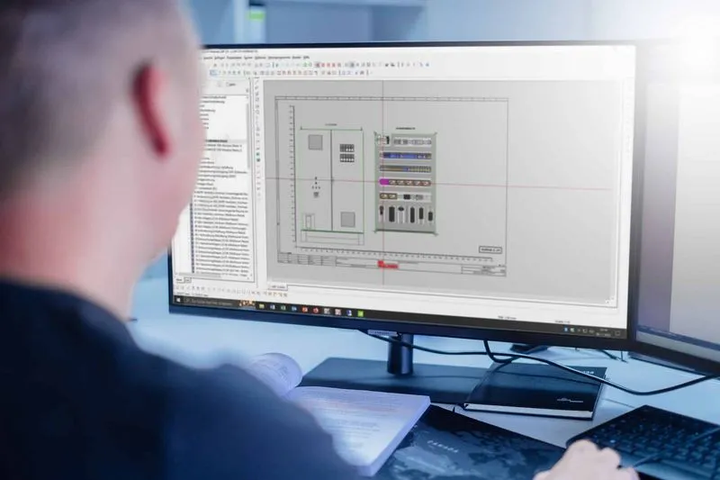 Person betrachtet einen PC-Bildschirm mit technischem Schaltplan für Schaltschrankbau.