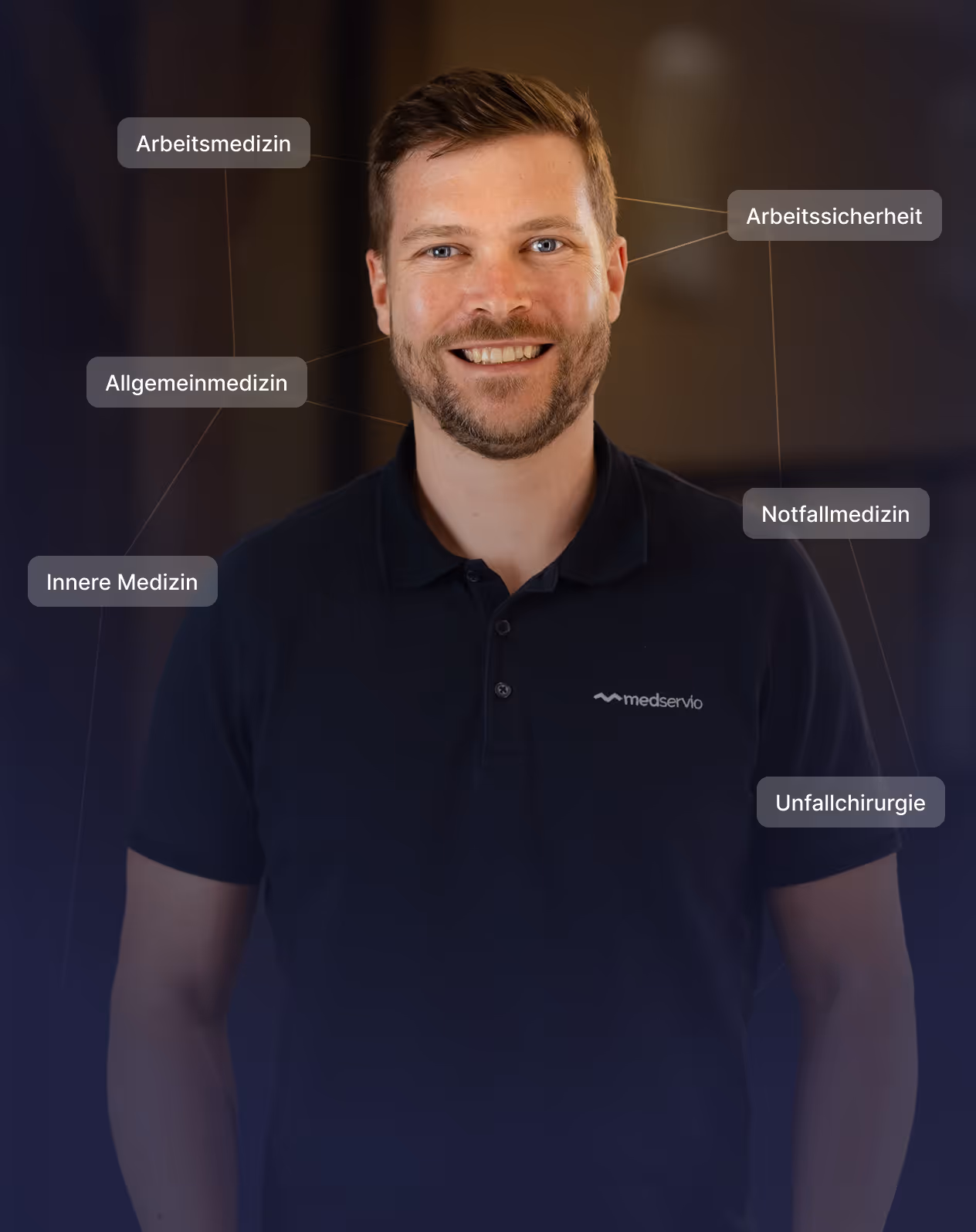 Smiling man wearing a black medservio polo shirt, surrounded by labels in German for medical fields including occupational medicine, general medicine, internal medicine, occupational safety, emergency medicine, and trauma surgery.