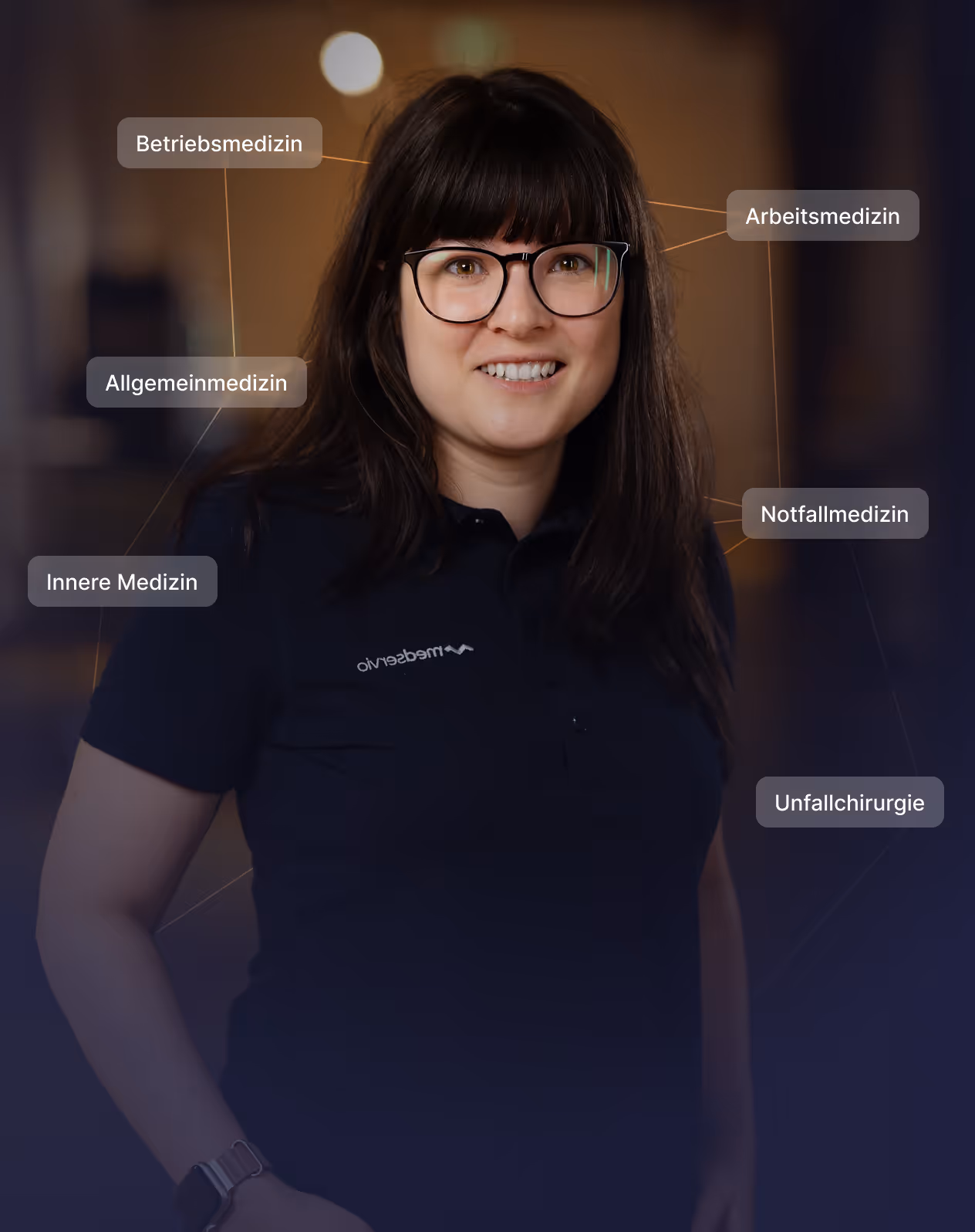 Smiling man wearing a black medservio polo shirt, surrounded by labels in German for medical fields including occupational medicine, general medicine, internal medicine, occupational safety, emergency medicine, and trauma surgery.