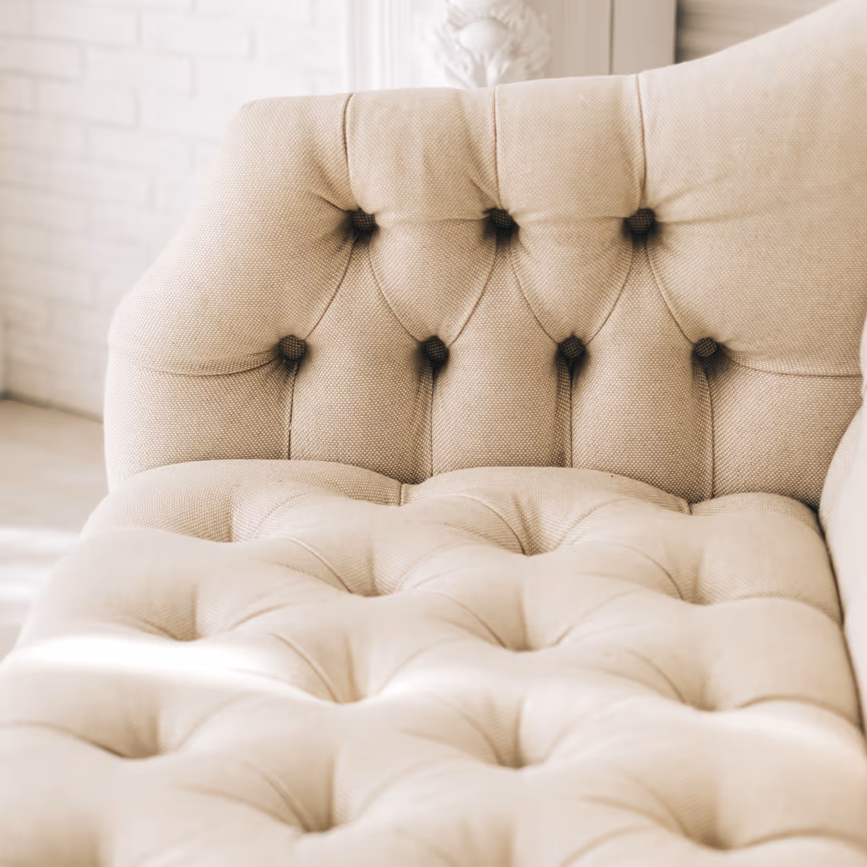 Close-up of beige tufted fabric upholstery on a cushioned sofa with button details.