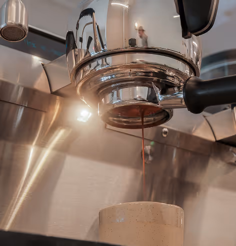 Close-up of espresso machine brewing coffee into a ceramic cup.
