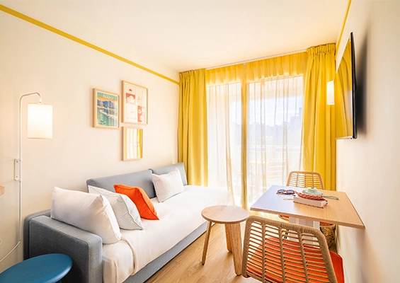 Soléo Prado, living room of the Privilege bedroom in Marseille with table and convertible bench, practical space in the Prado district.