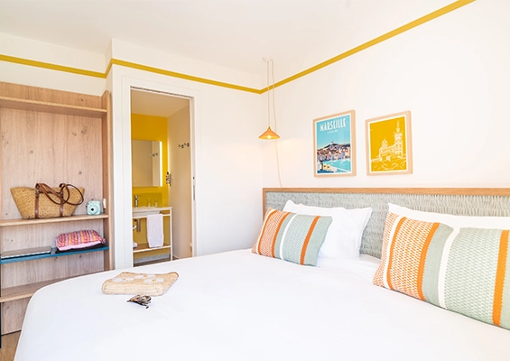 Soléo Prado, hotel room in Marseille with double bed and colored headboard, original atmosphere in the Prado district.