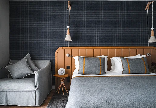 Intérieur d'une chambre supérieure de l'Heliopic Hotel & Spa, avec un lit, une table de chevet et un fauteuil convertible.