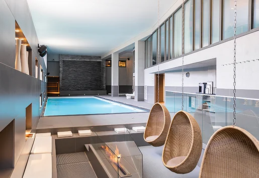 L'espace tisanerie du spa NUXE de l'Heliopic Hotel & Spa à Chamonix, avec la piscine et la cascade murale en arrière-plan.