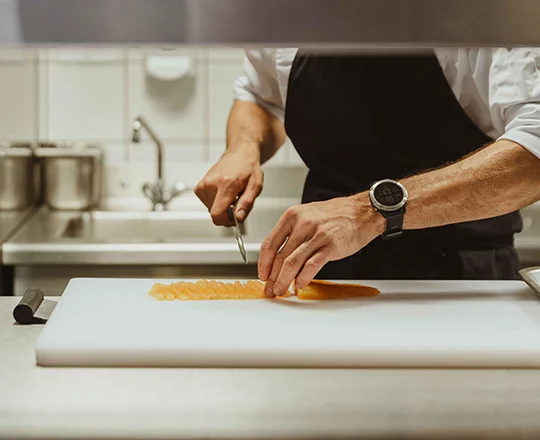 Membre de la cuisine du restaurant Goldlockchen du Braunbär Hotel & Spa découpant du poisson