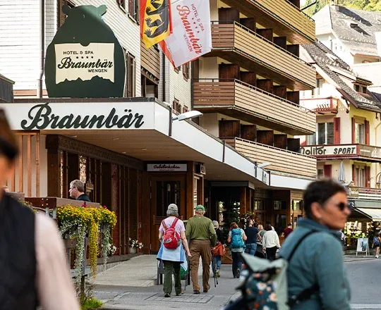La rue piétonne du village de Wengen passant devant l'entrée du Braunbär Hotel & Spa avec de nombreux piétons