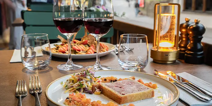 repas en terrasse au restaurant Goldockchen avec un pâté en croute en entrée et des verres de vin rouge