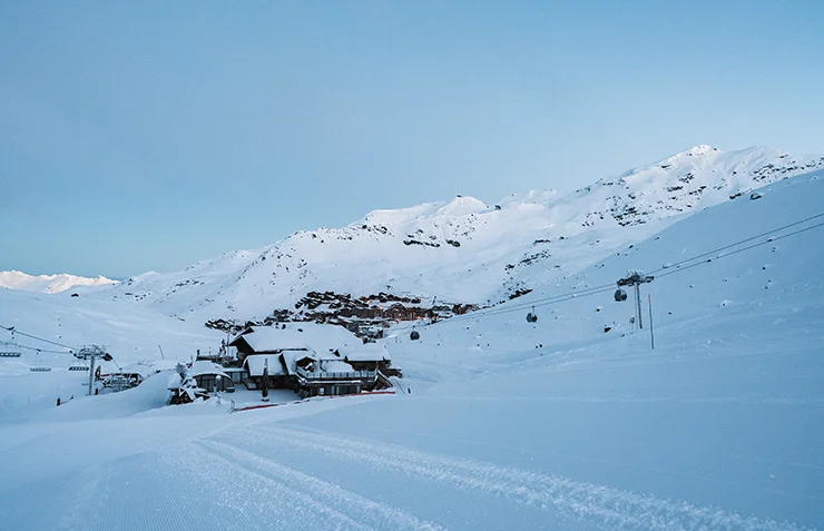 Le village de Val Thorens et son domaine skiable recouvert de neige, photographiés depuis les pistes de ski de la station lors d'un lever de soleil en hiver.