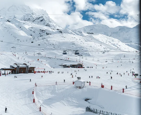 Le domaine skiable de Val Thorens avec ses nombreux skieurs, vu depuis le balcon d'une des chambres de l'hôtel Marielle, sous un ciel nuageux mais ensoleillé.