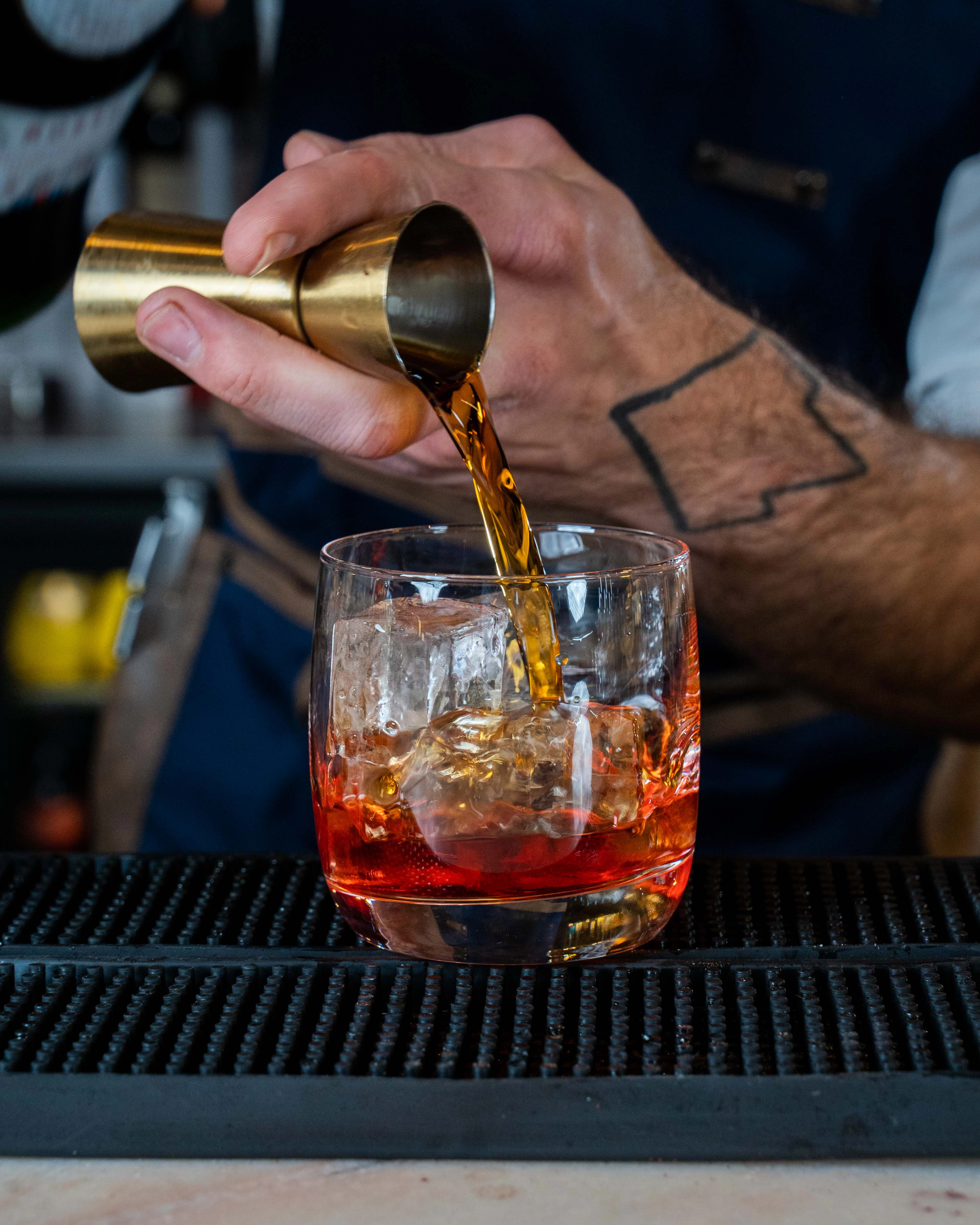 Un bartender préparant un cocktail en versant de l'alcool dans un verre à mixer