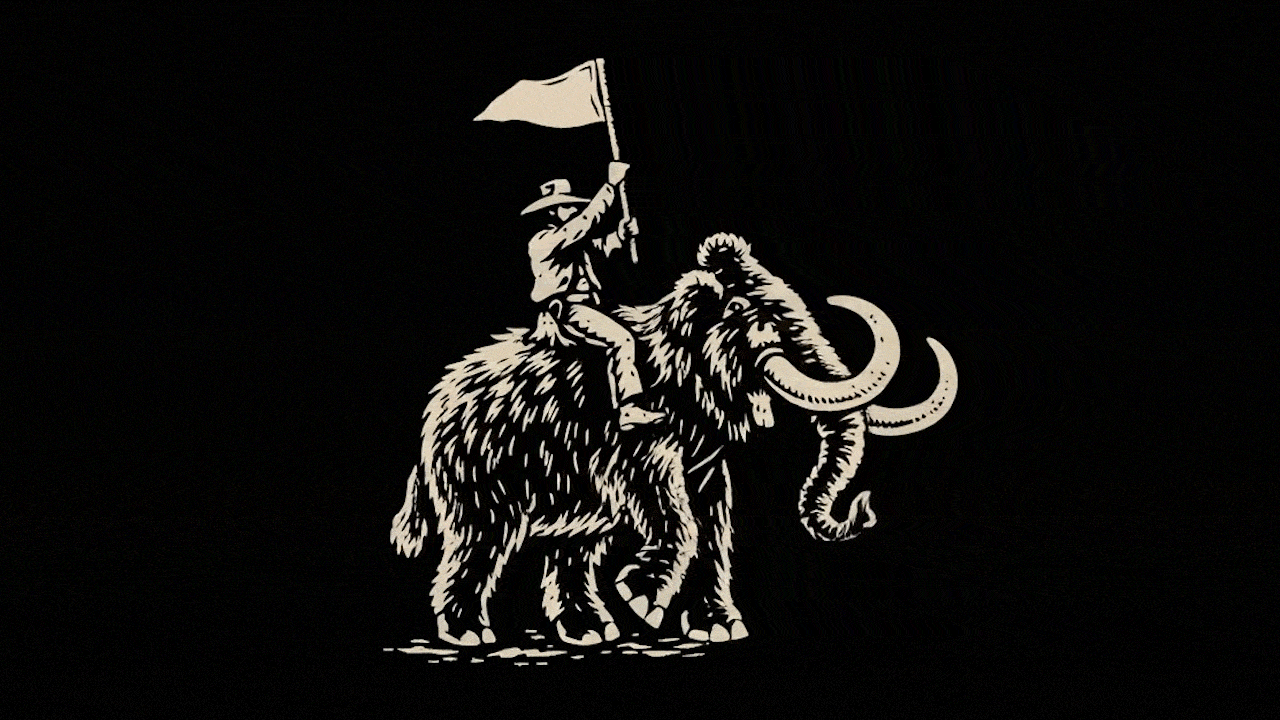 Woman embraces young girl from behind as they both look at a laptop screen on a wooden table.