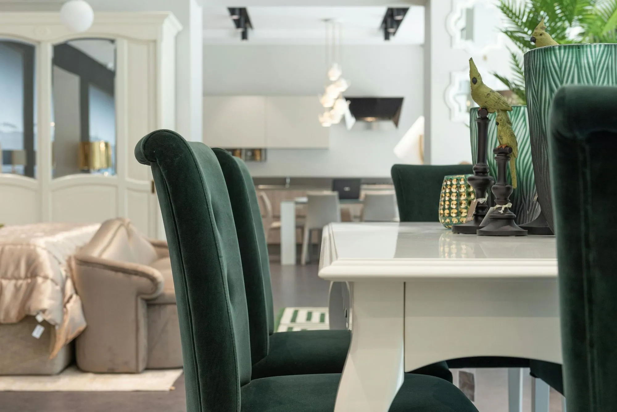 Close-up of dark green velvet dining chairs around a white table with decorative accents