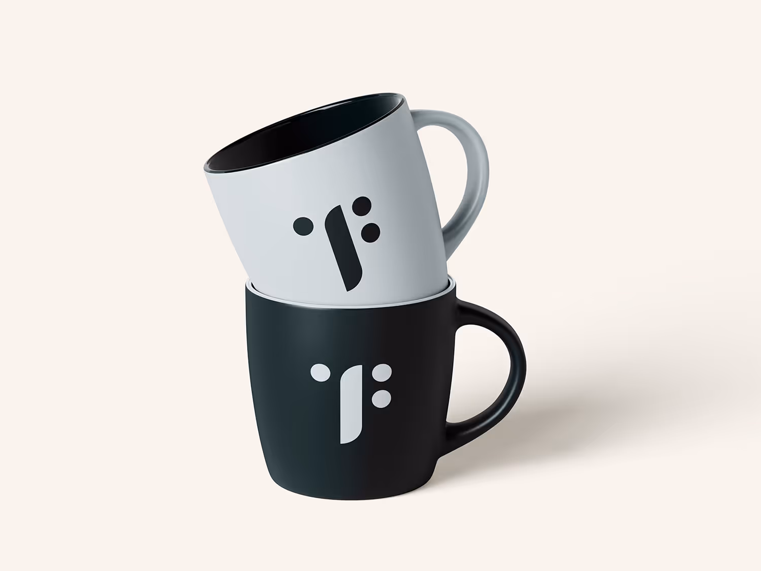 To kaffekopper stablet, en svart kopp under og en hvit kopp med sort innside oppå, begge med minimalistisk design på siden.