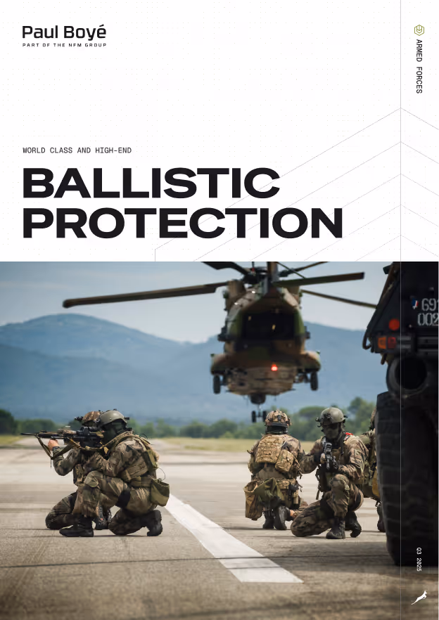 Soldater i kamuflasjeuniformer med våpen på kne på en landingsbane, et militærhelikopter svever foran fjell i bakgrunnen.