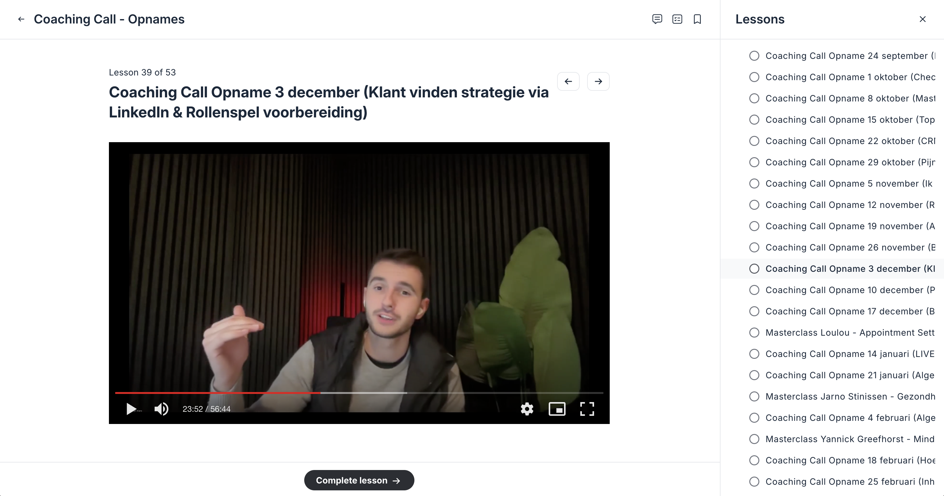 Man legt een coaching call uit in een video-opname met een donkere achtergrond en grote groene bladeren rechts.