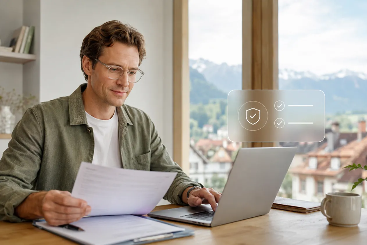 Man wearing glasses sitting at a wooden desk near a window with a scenic mountain view, holding a paper and working on a laptop with digital icons symbolizing security and task completion floating above the laptop.