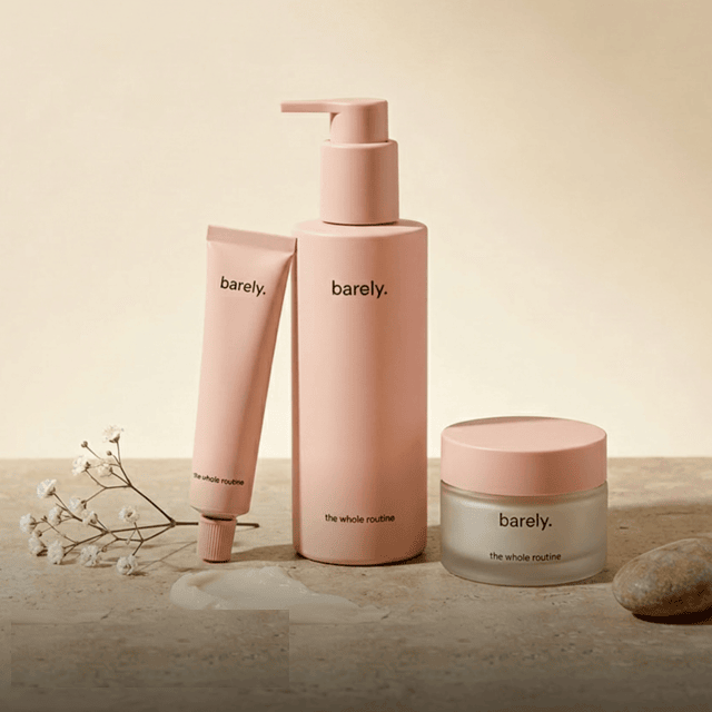 Three pink Barely skincare products displayed on a stone surface