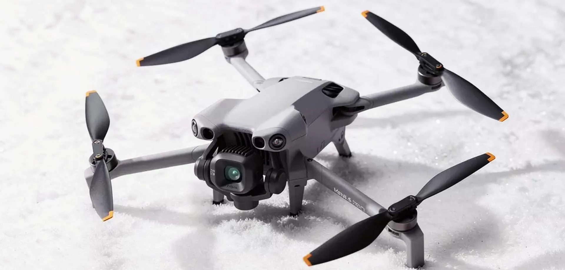 Graue Drohne mit Kamera und vier Propeller auf Schnee.