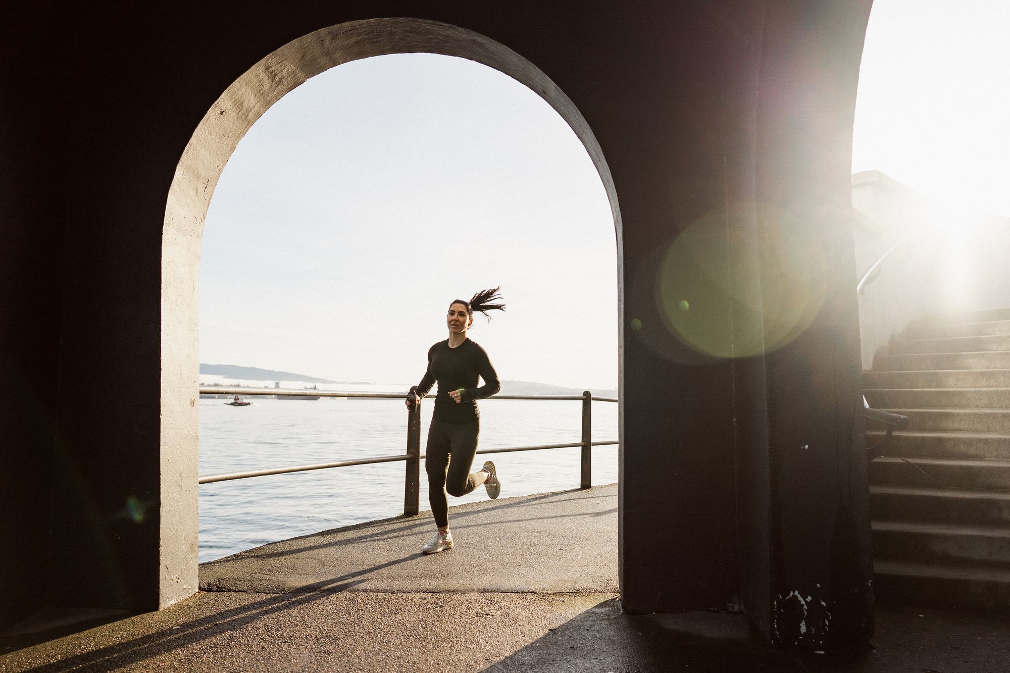 Runner on the seawall framed by a stone arch