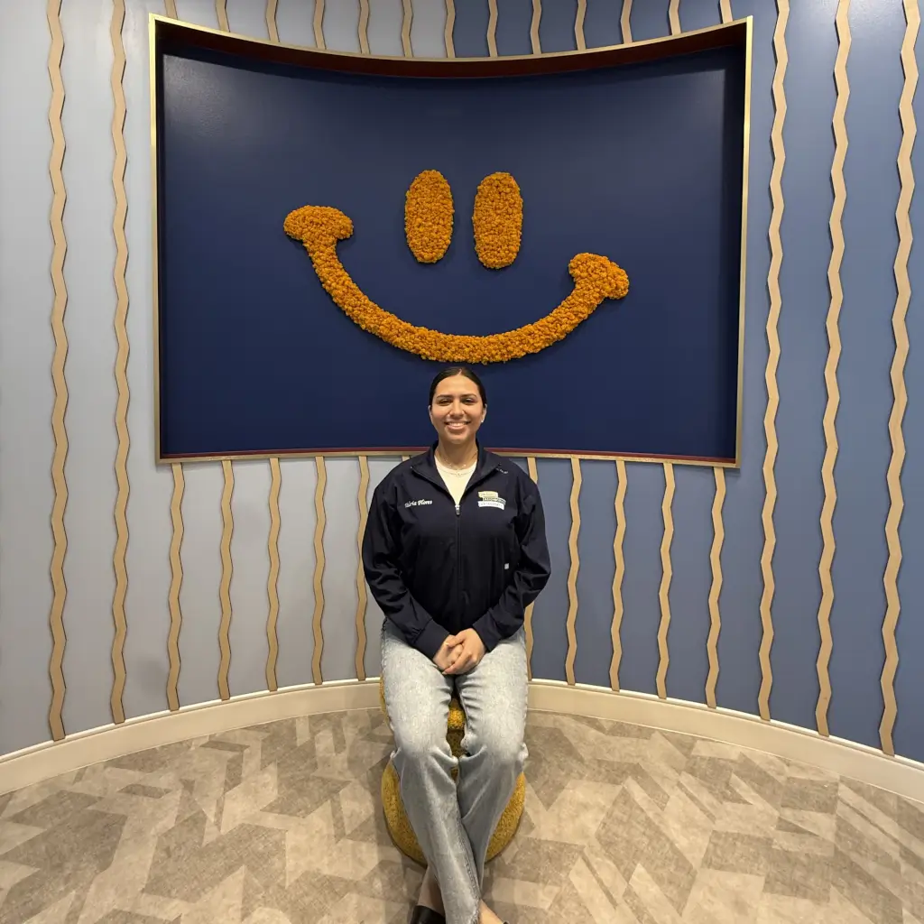 Valeria, team member at Friendly Neighborhood Orthodontist, at the Smile Corner wall