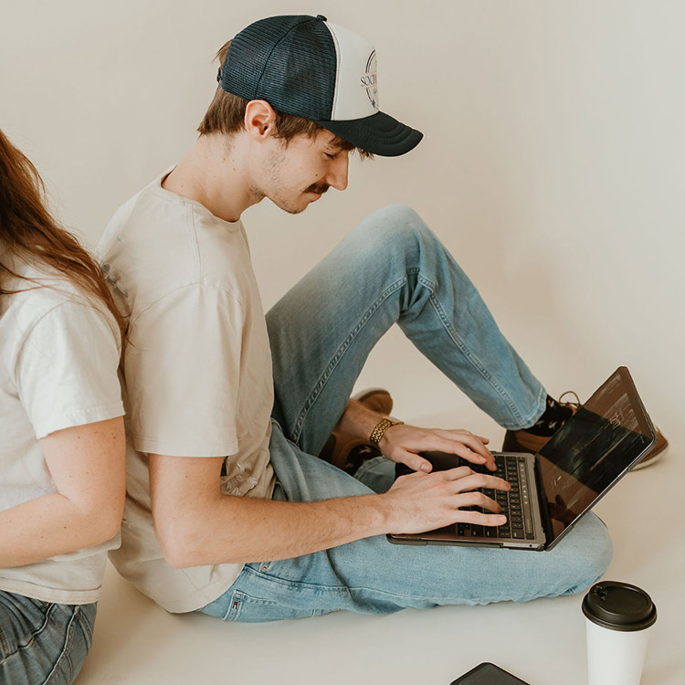 Team member from The Social Circle working on a laptop while seated beside another team member in a creative studio setting